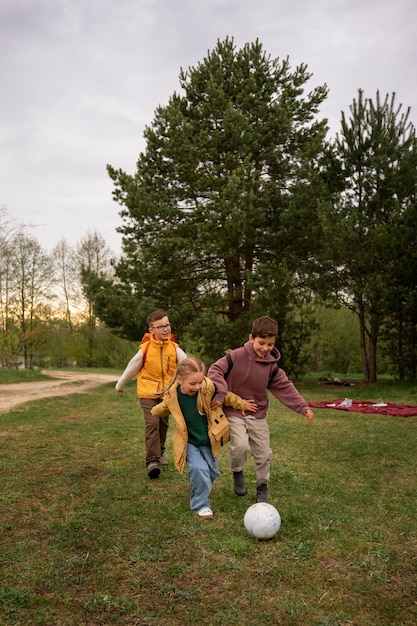 バックパックを背負って自然の中でボール遊びをする小さな子供たちの眺め