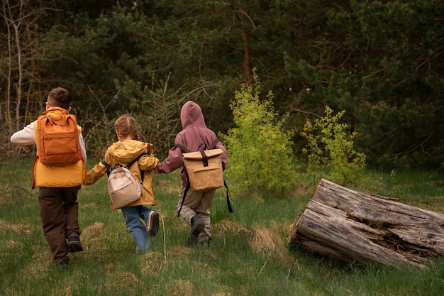 Free photo view of little kids with backpacks spending time in nature outdoors