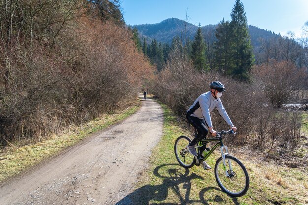 コロナウイルス検疫中に木々に囲まれた道路の自転車に乗っている男性の様子