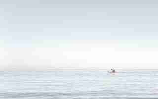 Foto gratuita vista di un uomo che fa kayak sull'acqua molto calma sul mare