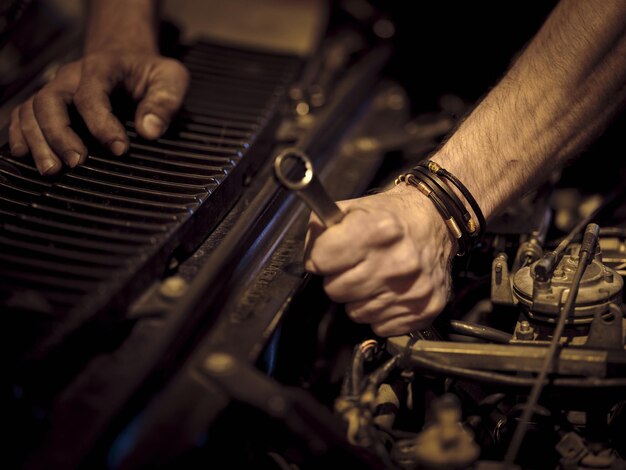 Вид на сильные руки мужчины с кожаными браслетами, фиксирующими механизм машины