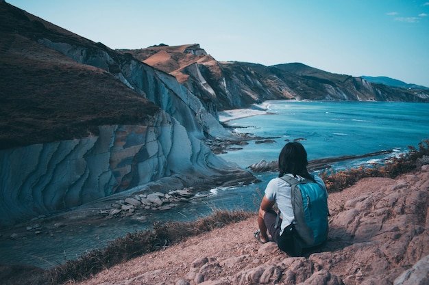 View of man sitting with a rocky hill background