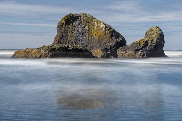 Вид на таинственный остров с его отражением на поверхности моря на фоне пасмурного дня