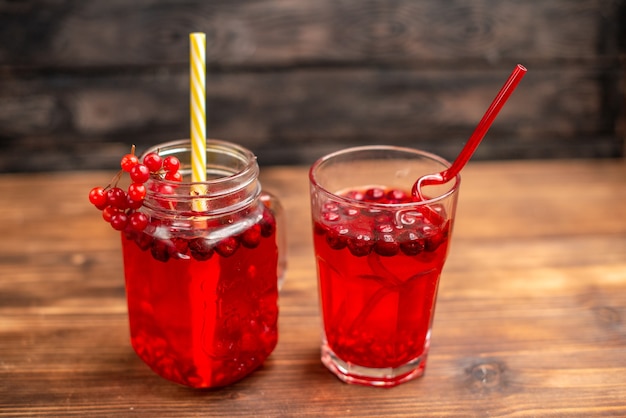 Above view of natural organic fresh currant juice in a glass and a bottle served with tubes on a wooden table