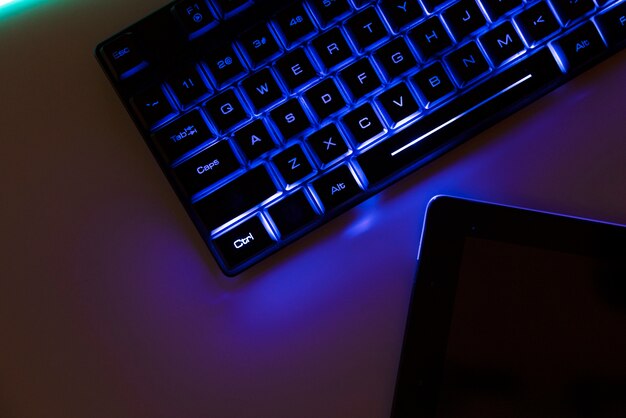 View of neon illuminated gaming desk setup with keyboard