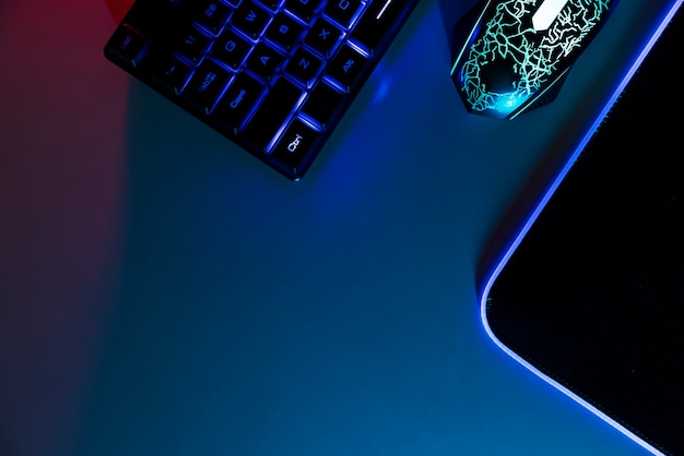 View of neon illuminated gaming desk setup with keyboard