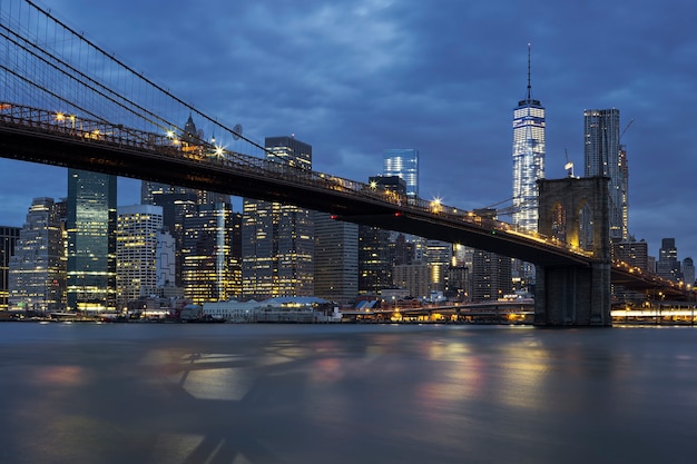 View of New York City Manhattan midtown at dusk with Brooklyn Bridge.