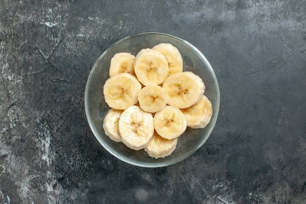 Sopra vista fonte di nutrizione banane fresche tritate in un coltello da vaso di vetro su sfondo grigio