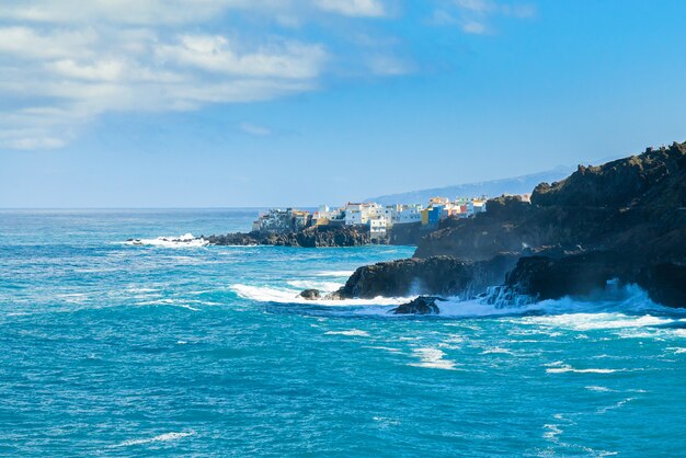 プンタブラバ、プエルトデラクルーズ、テネリフェ島、カナリア諸島、スペインの岩の上の海の海岸とカラフルな建物を見る