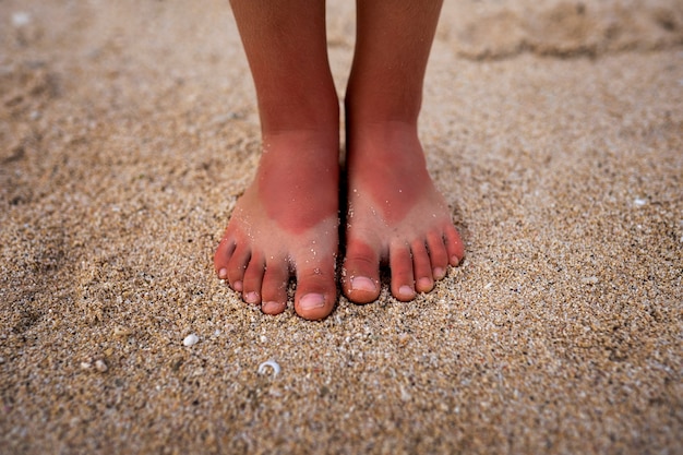 無料写真 ビーチでサンダルを履いて日焼けした子供の足のビュー