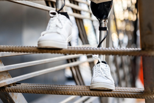 無料写真 義足と白いスニーカーで金属製の階段を登る男性のビュー