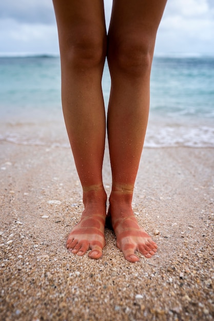 無料写真 ビーチでサンダルを履いて日焼けした女性の足のビュー
