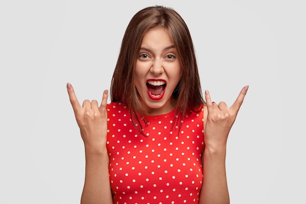 Бесплатное фото Вид крутой европейской женщины делает рок-жест, безумно восклицает
