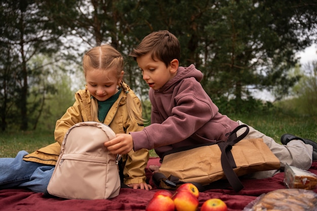 Бесплатное фото Вид маленьких детей с рюкзаками, проводящих время на природе на открытом воздухе