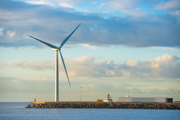 Вид на морской залив и большую ветряную мельницу на краю каменного волнолома
