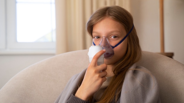 무료 사진 호흡기 건강 문제를 위해 집에서 분무기를 사용하는 십대 소녀의 모습