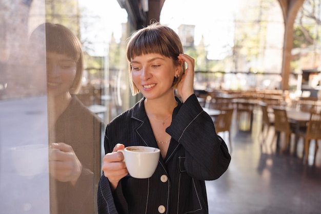 無料写真 一杯のコーヒーと笑顔を保持している女性のビュー