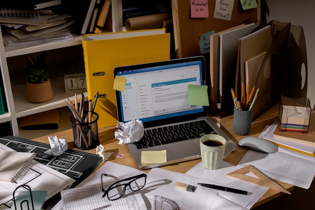 Free photo view of office desk with messy workspace and laptop