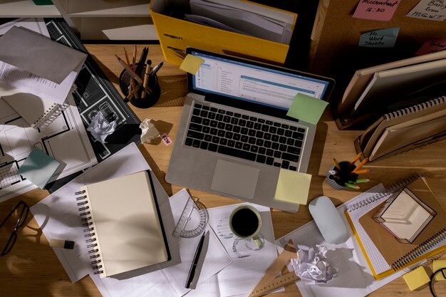 View of office desk with messy workspace and laptop