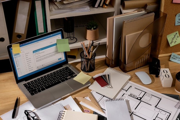 Foto gratuita vista della scrivania dell'ufficio con un'area di lavoro disordinata e un computer portatile