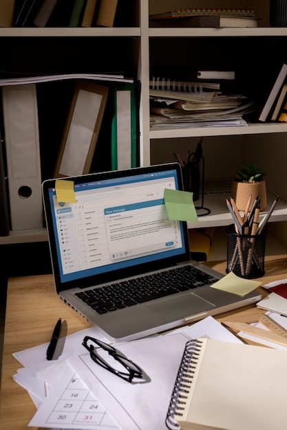 Free photo view of office desk with messy workspace and laptop