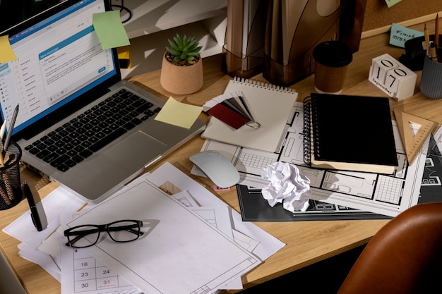 Free photo view of office desk with messy workspace and laptop