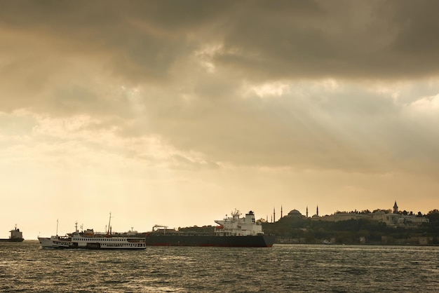 View of the old historical building with mosques towers buildings in the eastern style cargo ships tugboats in the port on the roadstead on the background of cloudy sky