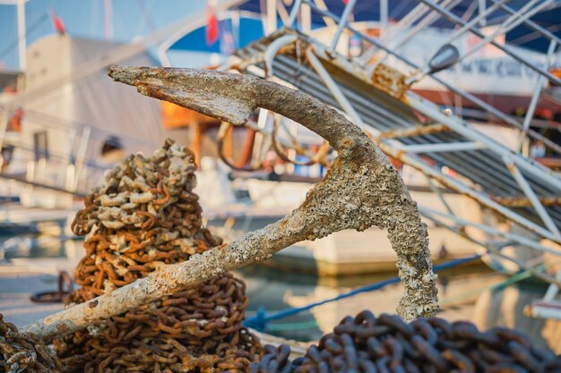 View of the old rusty anchor with a chain in the port of the city Anchor of an old ship on the pier selective focus background or screen about holidays at sea and travel