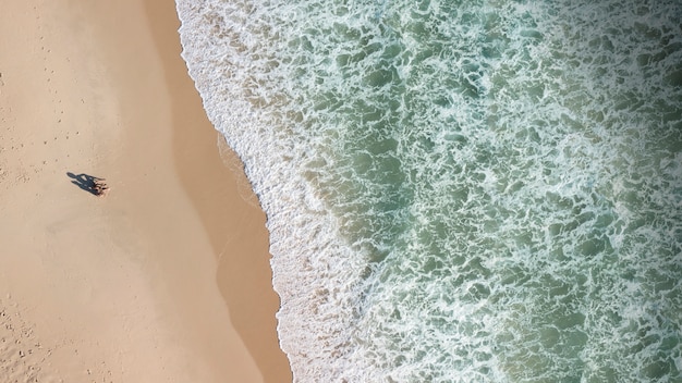 View of people on seashore and foam waves