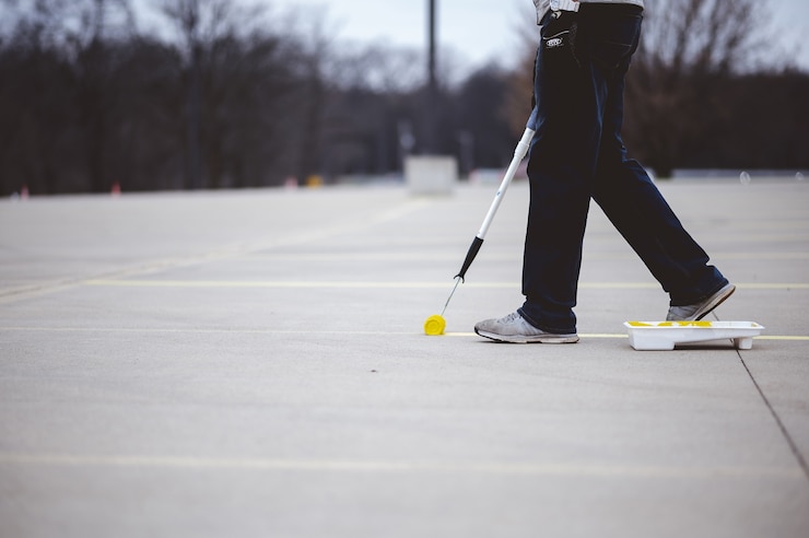 Free Photo view of a person repainting the parking lines on the asphalt of a parking lot with yellow paint