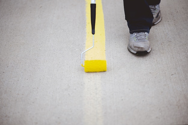 Free photo view of a person repainting the parking lines of the asphalt of a parking lot with yellow paint