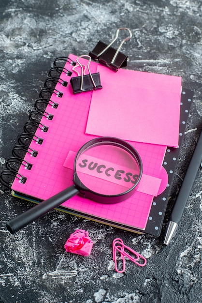 Free photo above view pink notepad with pen magnifier and success note on gray background