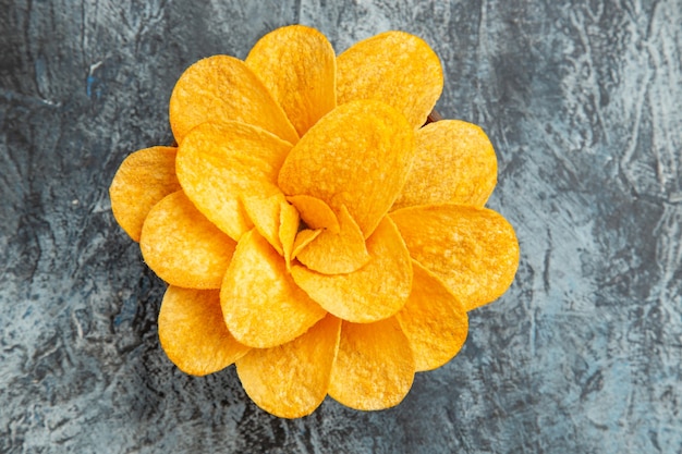 Above view of potato chips decorated like flower shaped in a brown bowl on gray table