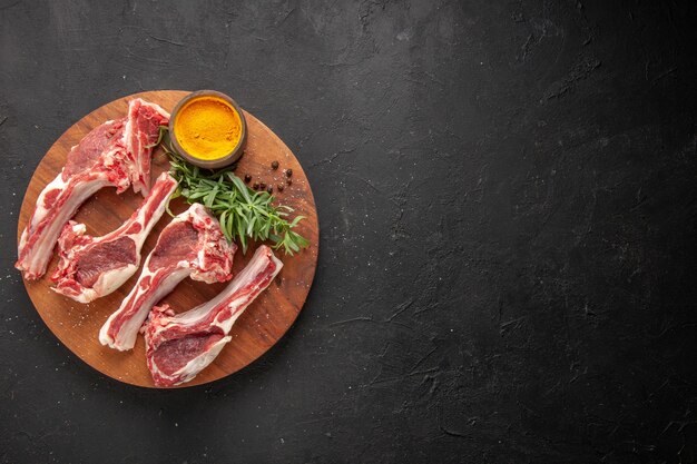 Above view of red meat green yellow ginger on a wooden cutting board on the left side on dark