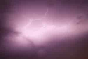 Free photo view of the sky capturing a bolt of lightning with purple cloudy skies
