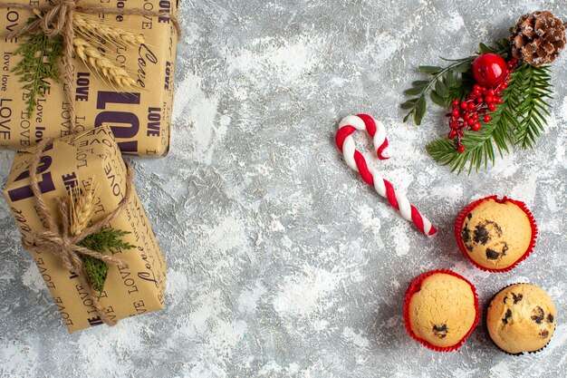 얼음 표면에 작은 컵 케이크 사탕과 전나무 가지 장식 액세서리 및 선물보기 위
