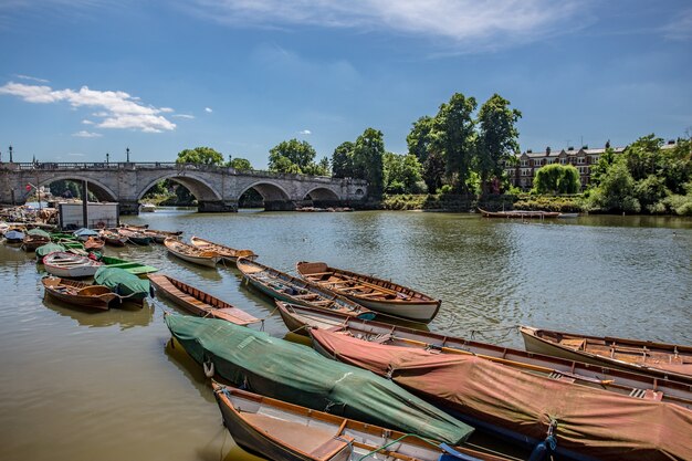 View of small wooden boats in the Thames river near an old bridge