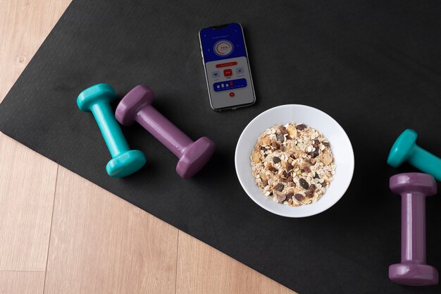 View of smartphone with weights and cereal bowl