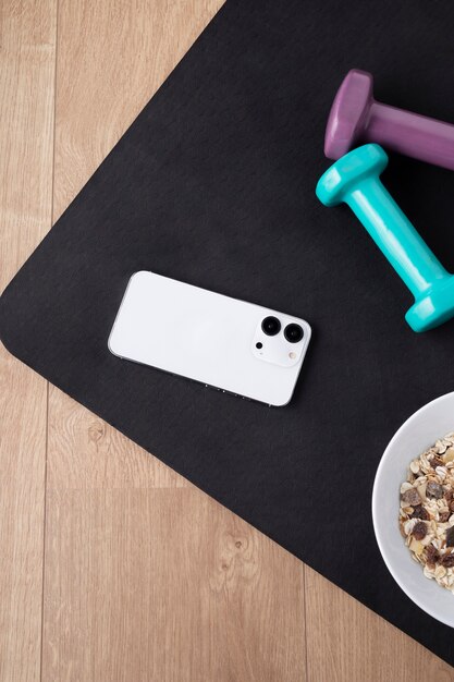 View of smartphone with weights and cereal bowl