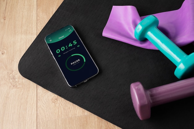 Вид смартфона с гирями и ковриком для йоги