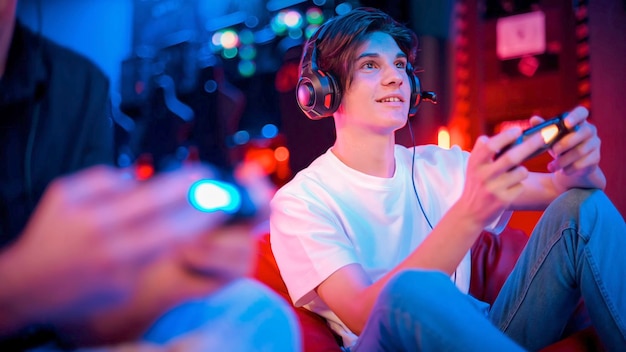 Free photo view of a smiling teen playing a game console in headphones using gamepad