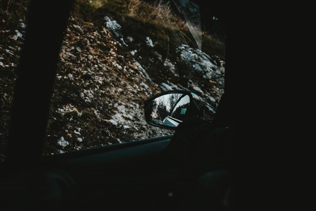 View of the snow covered hills and trees captured from a car window and the side mirror