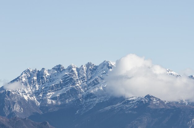 View of a snow-covered rocky mountain partially covered with clouds