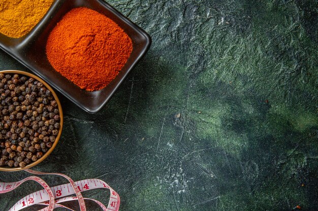 Above view of spice bowls fulfilled with red pepper and yellow ginger meter on mix colors surface