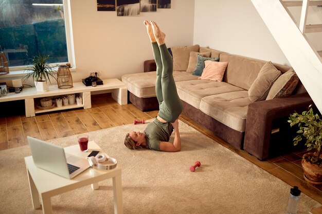 Above view of sportswoman doing supported shoulderstand while working out at home