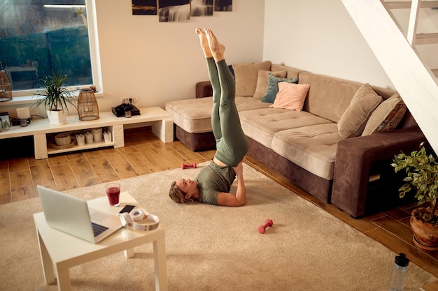 Above view of sportswoman doing supported shoulderstand while working out at home