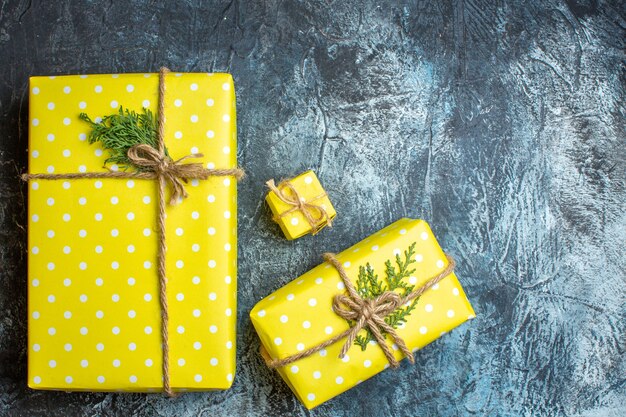 Above view of stacked beautiful yellow Christmas gift boxes for family members on dark background