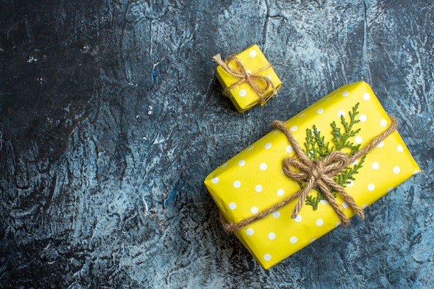 Above view of stacked beautiful yellow Christmas gift boxes for family members on the left side on dark background