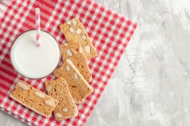 Sopra la vista di caramelle a forma di bastone in tazza di vetro e pasticcini su asciugamano rosso su sfondo grigio