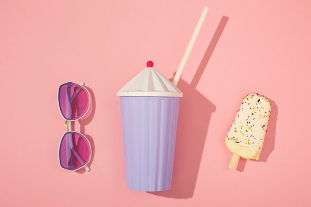 View of summer sunglasses with drink and straw